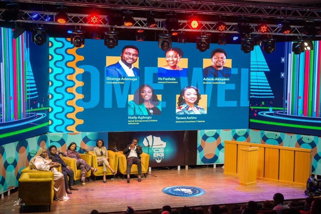Panel session on a theatre stage under a wide LED wall with angled wing screens